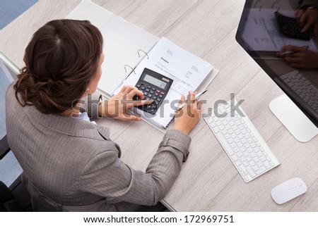 High Angle View Of Young Female Accountant Calculating Bills