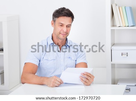 Happy Mature Man Reading Paper Holding In Hands