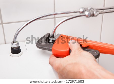 Close-up Of Plumber\'s Hand Fixing Household Fixture In Bathroom