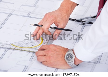 Close-up Of Male Architect Drawing Blueprint In Office