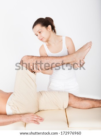 Young Man Lying On Table Getting Foot Massage From Masseuse