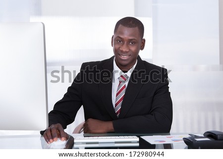 Happy Young African Businessman Using Computer At Desk