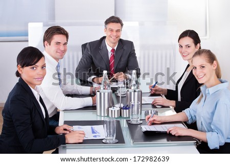 Portrait Of Happy Businesspeople Sitting At Desk Sharing Idea