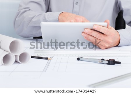 Close-up Of Architect Using Digital Tablet  Over Blueprint