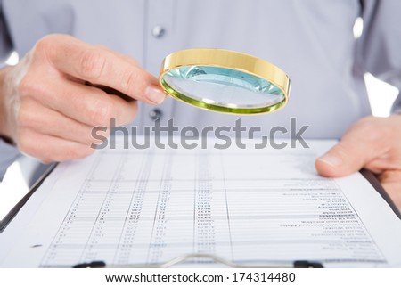 Businessman Looking At Document Through Magnifying Glass On White Background