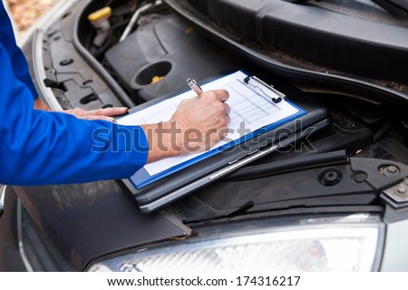 Close-up Of A Mature Mechanic Maintaining Car Records