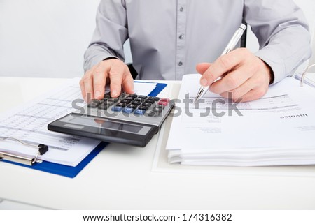 Close-up Of A Man With Financial Bills Using Calculator