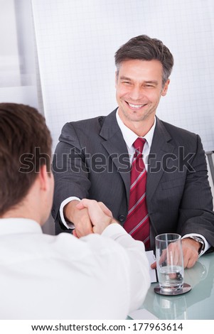 Portrait Of Happy Mature Businessman Conducting Interview In Office