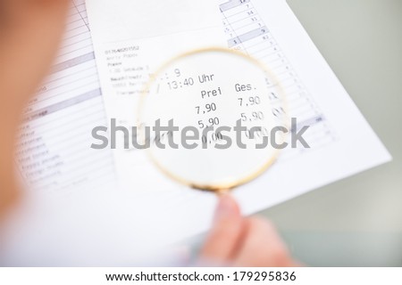 Close-up Of Hand Holding Magnifier Over Document