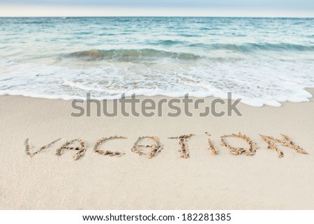 Word Vacation written in sand on beach