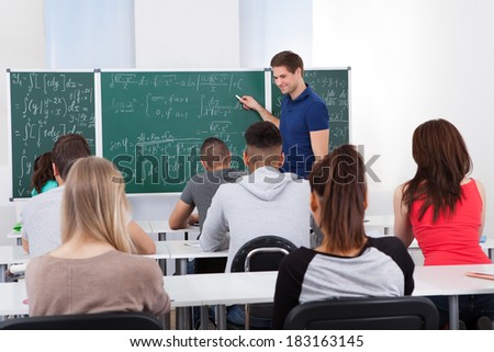 Young teacher teaching mathematics to college students in classroom