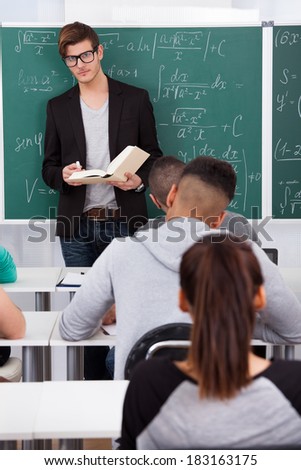 Young teacher teaching mathematics to university students in classroom