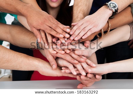 Cropped image of university students piling hands at desk