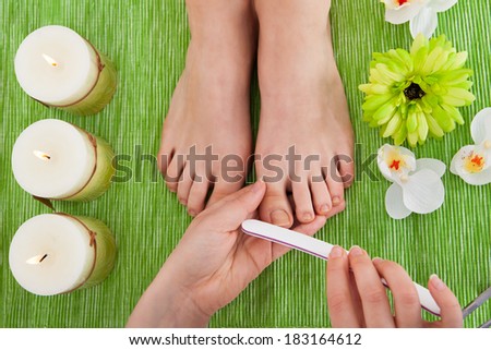 High Angle View Of Beautician Hand Filing Nails Of Woman In Salon