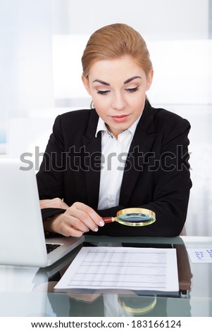 Businesswoman Looking At Document Through Magnifying Glass