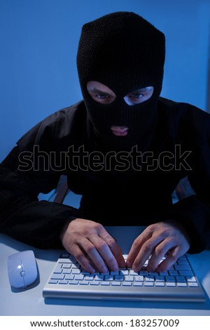 Criminal using computer to hack online account at table