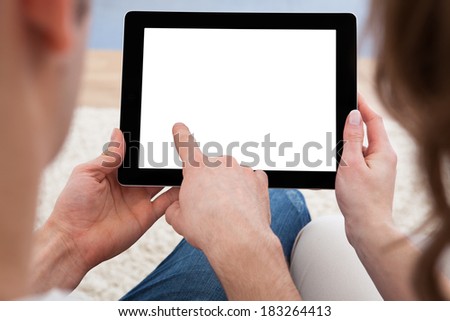Beautiful young couple sitting side by side on a sofa looking at a tablet together