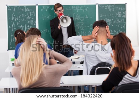 Young teacher shouting through megaphone on university students in classroom