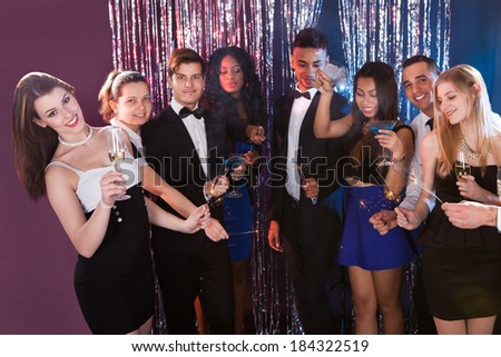 Happy multiethnic friends holding sparkling sticks at nightclub