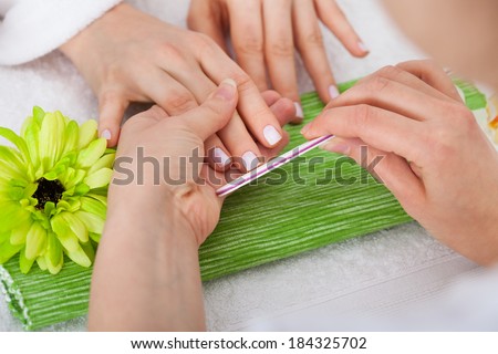 Close-up Of Beautician Hand Filing The Nails Of Woman In Salon