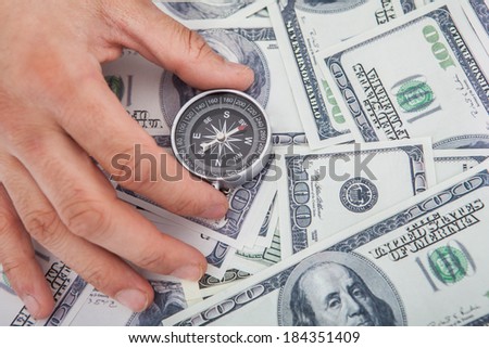 Cropped image of hand holding compass on US paper currency