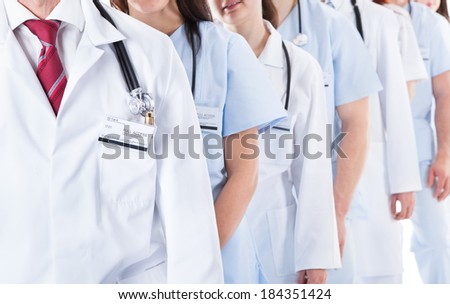 Long receding line or queue of smiling doctors and nurses in white uniforms wearing stethoscopes around their necks isolated on white