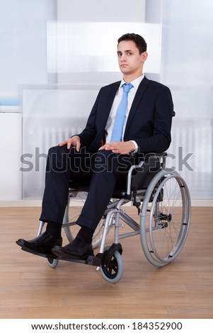 Portrait of confident disabled businessman sitting on wheelchair in office