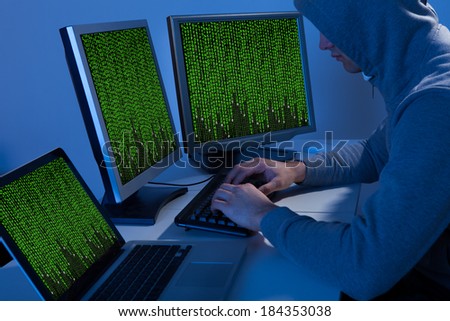 High angle view of hacker in hooded jacket using computer at table