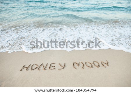 Word Honeymoon written in sand on beach