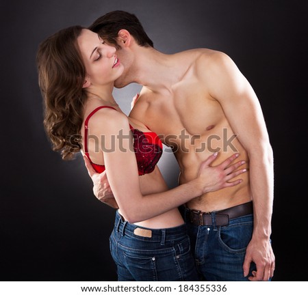 Young passionate man kissing woman\'s neck isolated over black background