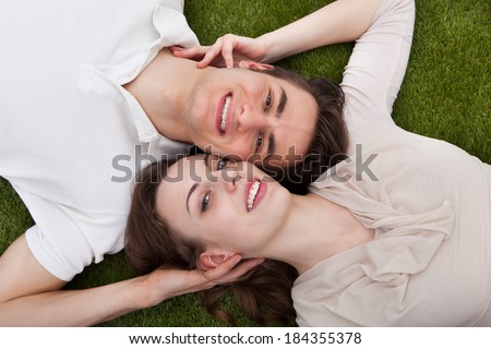 Directly above portrait of loving young couple lying on grass