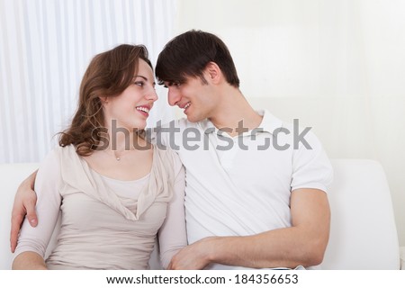 Affectionate couple relaxing on a sofa with the mans arm around his wifes shoulders