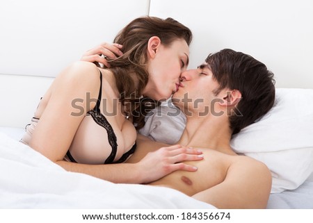 Young intimate couple kissing each other in bed at home