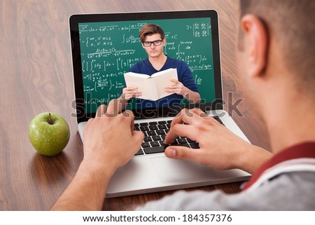 Male college student attending online math\'s lecture on laptop