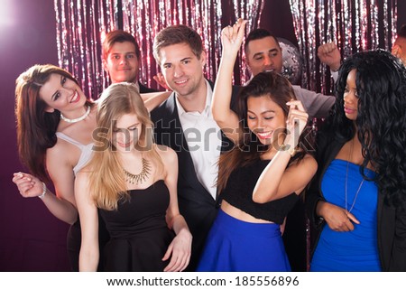 Portrait of cheerful young friends dancing in nightclub