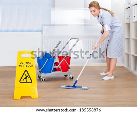 Portrait Of Young Maid Cleaning Floor With Mop