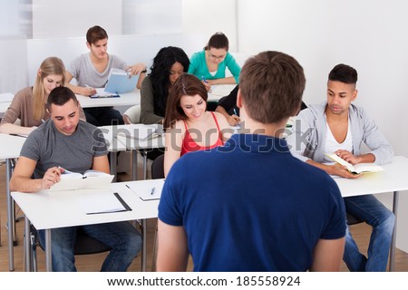 Rear view of teacher teaching university students in classroom