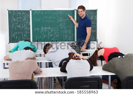 Young teacher teaching mathematics to bored college students in classroom