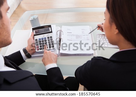 High angle view of business people calculating tax together at desk in office