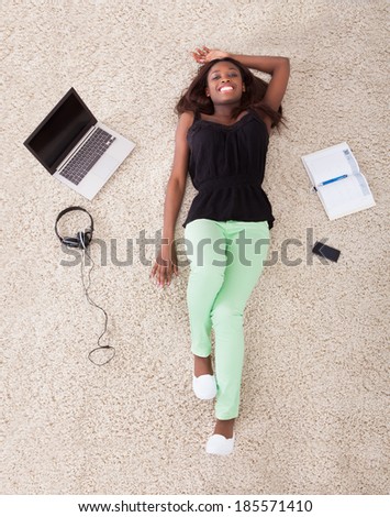 High angle view of young African American woman relaxing on rug at home