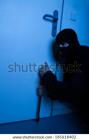 Thief opening door with crowbar during house breaking