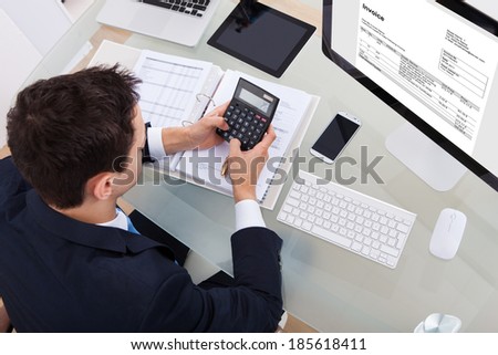 High angle view of businessman calculating tax at desk in office
