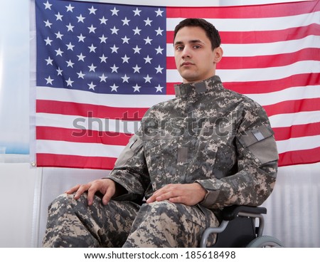 Cropped image of patriotic soldier sitting on wheel chair against American flag