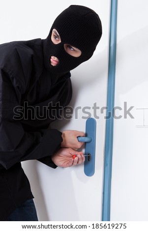 Alert thief looking away while opening door with tool during house breaking