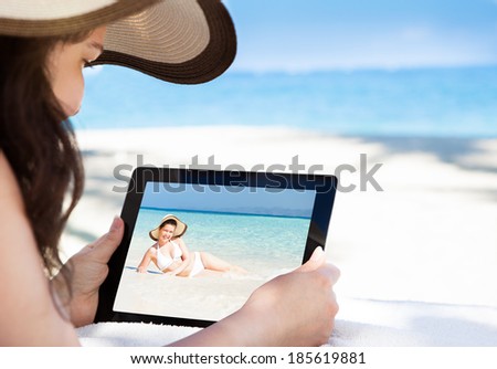 Cropped image of woman looking at her picture on digital tablet at beach