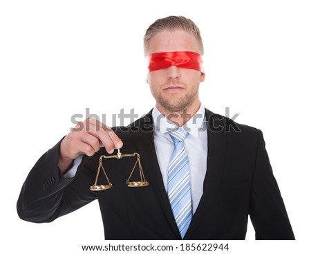 Lawyer or judge with the scales of justice in his hand wearing a blindfold  conceptual of impartiality and fairness