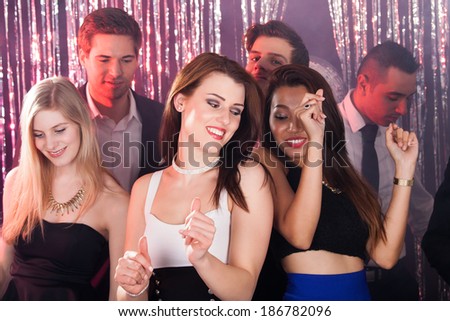 Portrait of happy young women dancing with friends at nightclub