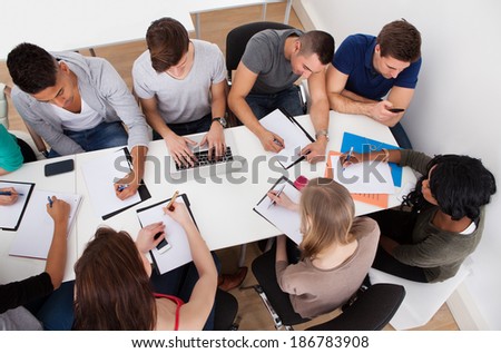 High angle view of university students doing group study at desk in classroom