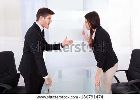 Side view of business people quarreling at desk in office