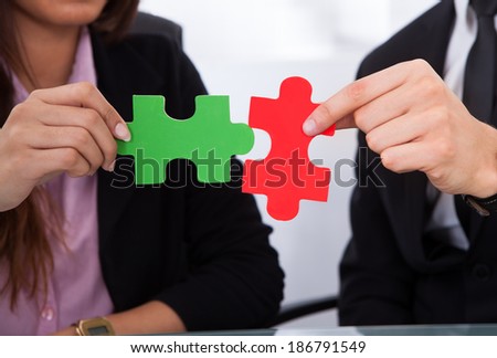 Cropped image of hands joining puzzle pieces